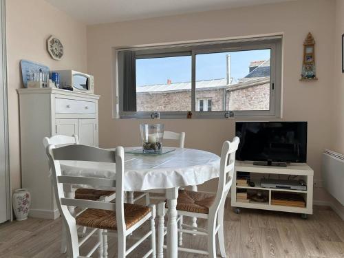 une salle à manger avec une table et des chaises et une fenêtre dans l'établissement 504 - A Erquy, en bordure de la plage du centre, à 800m des commerces, à Erquy