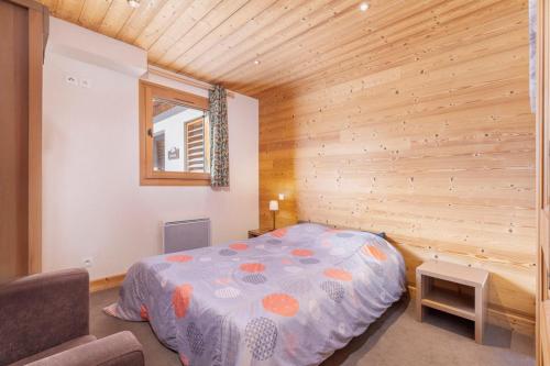ein Schlafzimmer mit einem Bett in einer Holzwand in der Unterkunft Résidence Dormio Resort Les Portes du Grand Massif - Flaine in Flaine