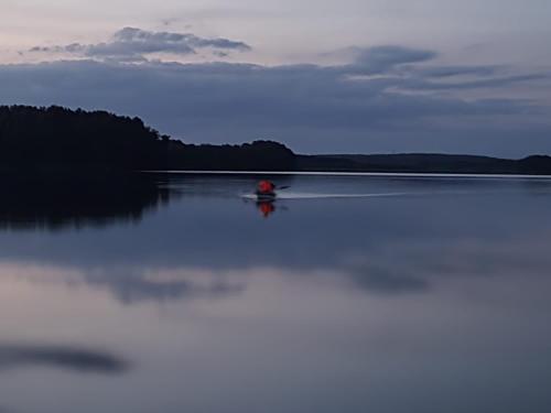 a person in a kayak on a lake at dusk at Urlaub am Plätlinsee Haus Rike in Wustrow