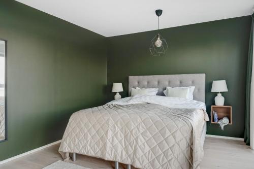 a bedroom with green walls and a large bed at Guestly Homes - 4BR Serene Villa with Garden in Nyköping