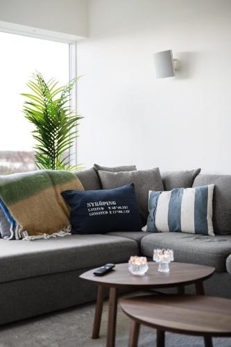 a living room with a couch with pillows and a table at Guestly Homes - 4BR Serene Villa with Garden in Nyköping