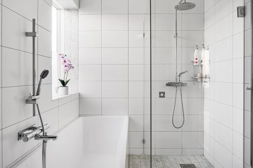 La salle de bains blanche est pourvue d'une douche avec une porte en verre. dans l'établissement Nyköping Villa: Serene & Stylish, à Nyköping