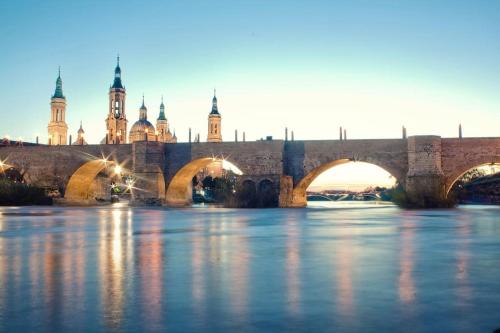 un puente sobre un río con una ciudad en el fondo en Loft LVU en Zaragoza, en Zaragoza