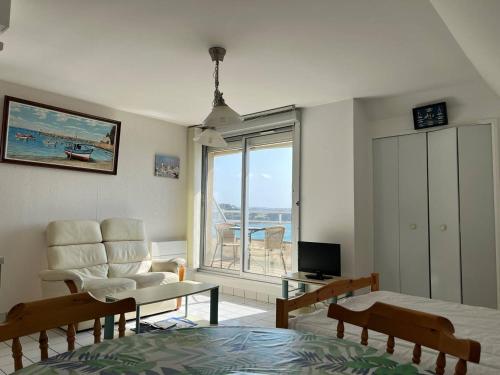 un salon avec un lit, une chaise et une fenêtre dans l'établissement 509 - Grand studio à Erquy au dernier étage, en bordure de la plage du centre, face au port de pêche, à Erquy