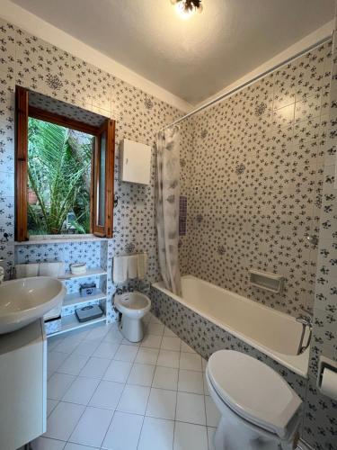 a bathroom with a tub and a toilet and a sink at Villa Le Palme in Ischia