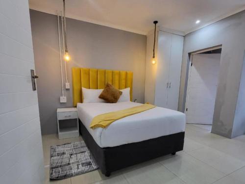 a bedroom with a large bed with a yellow headboard at Early Bird B&B in Nqutu