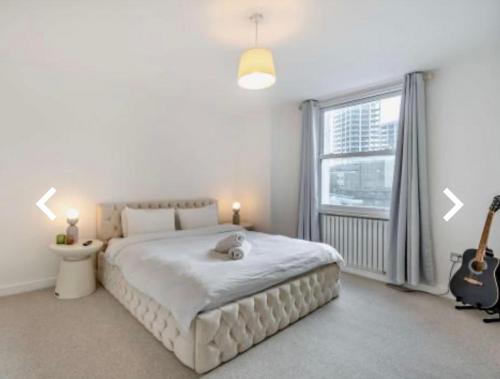 sypialnia z dużym białym łóżkiem i gitarą w obiekcie Stunning 2 bedroom flat Camden w Londynie