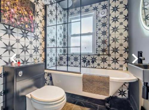 baño con bañera, aseo y ventana en Stunning 2 bedroom flat Camden en Londres
