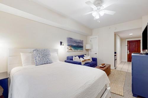 um quarto com uma cama branca e um sofá azul em Baytowne Wharf - Pilot House #207 em Destin