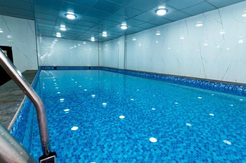 a large swimming pool with blue water in a room at Havana View hotel in Erbil