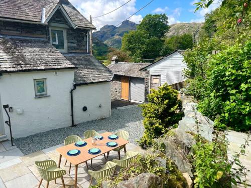 a patio with a table and chairs in front of a house at Langdale Boulders, Ambleside, Fantastic views in Chapel Stile