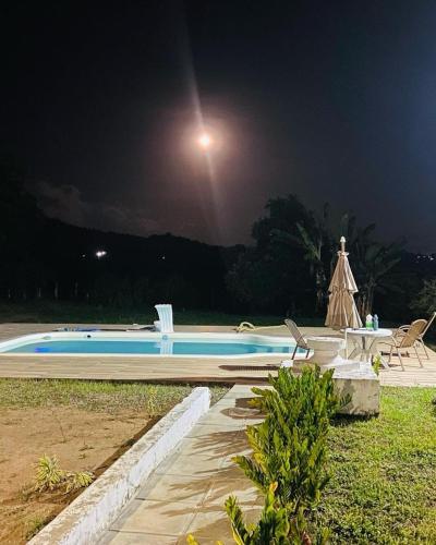 ein Schwimmbad in der Nacht mit einem Mond im Himmel in der Unterkunft Chácara Nascimento in Vitória de Santo Antão