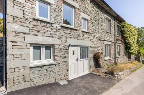 a stone house with a white door and windows at Langdale Boulders, Ambleside, Fantastic views in Chapel Stile