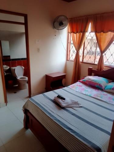 a bedroom with a bed and a toilet and a window at Samantha Hotel in Paz de Ariporo