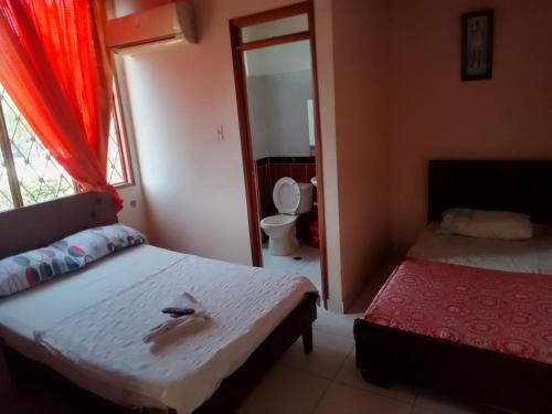 a bedroom with two beds and a window with a toilet at Samantha Hotel in Paz de Ariporo
