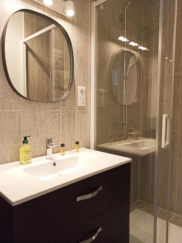 a bathroom with a sink and a shower with a mirror at Home Rental Service in Paris