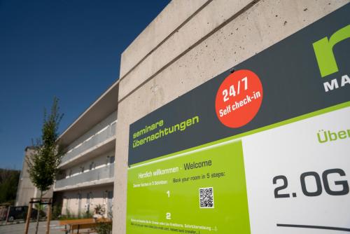 un edificio con un cartel en el costado en Mainfranken Motel - Anreise rund um die Uhr - Neueröffnung 2023, 