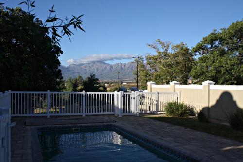 a swimming pool with a fence and mountains in the background at 1920s Charm on Waveren in Tulbagh