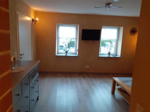 an empty room with two windows and a wooden floor at Am Eulenwald in Marpingen