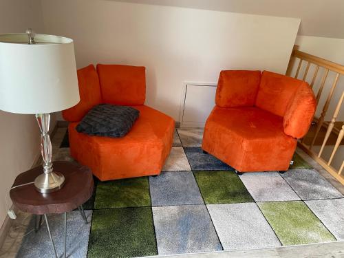 a living room with two orange chairs and a lamp at Urlaub am Plätlinsee Haus Rike in Wustrow