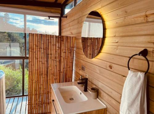 a bathroom with a sink and a mirror at Magma Home Cabaña Loft - Guatape Piscina-Jacuzzi in El Peñol