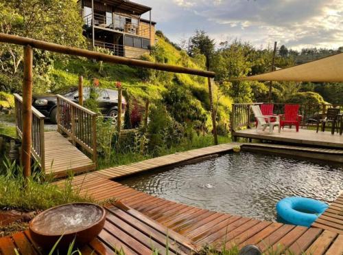 um quintal com uma piscina com um deque de madeira e um pátio em Magma Home Cabaña Loft - Guatape Piscina-Jacuzzi em El Peñol