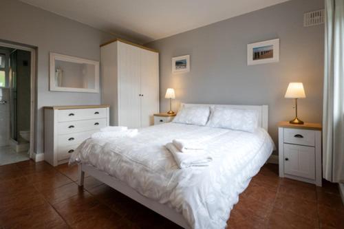 una camera da letto con un grande letto bianco e due comodini di Summerfield Lodge Garden Cottage a Youghal