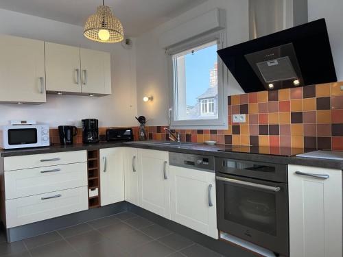 une cuisine avec des armoires blanches et un micro-ondes dans l'établissement 517 - Appartement T2, en plein cœur d'Erquy, à Erquy