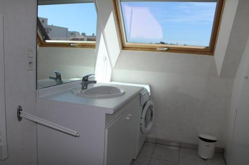 uma casa de banho branca com um lavatório e uma janela em 521 - Bel appartement avec balcon vue mer à Erquy en bordure de la plage du centre et à 300m des commerces em Erquy