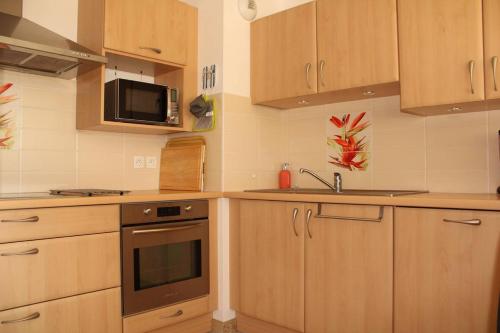 - une cuisine avec des placards en bois et un four micro-ondes dans l'établissement 528 - Appartement 2 chambres à Erquy, proche de la plage du Centre, à Erquy