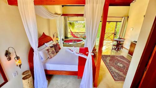 um quarto com uma cama e uma varanda com uma banheira em BANGATACHO - Bangalôs Temáticos na Praia do Patacho - Milagres em Porto de Pedras