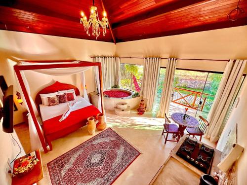 1 dormitorio con cama roja y espejo grande en BANGATACHO - Bangalôs Temáticos na Praia do Patacho - Milagres en Pôrto de Pedras