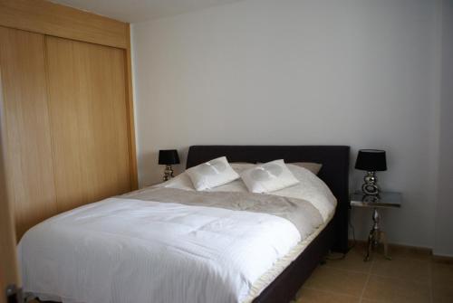 een slaapkamer met een bed met witte lakens en kussens bij Bella Vista- allermooiste appartement in El Campello