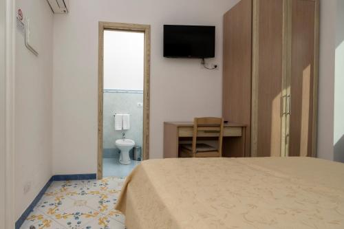 a bedroom with a bed and a desk and a television at Guest House La Piazzetta in Capri