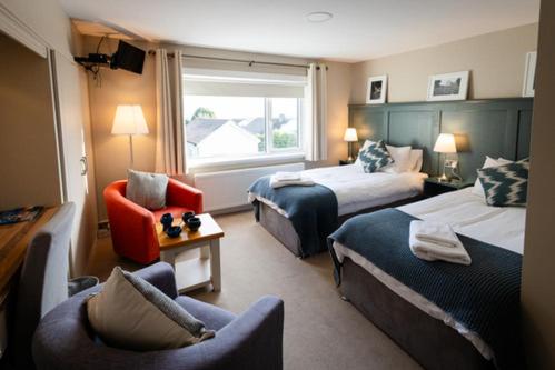 a hotel room with two beds and a chair at Summerfield Lodge B&B in Youghal