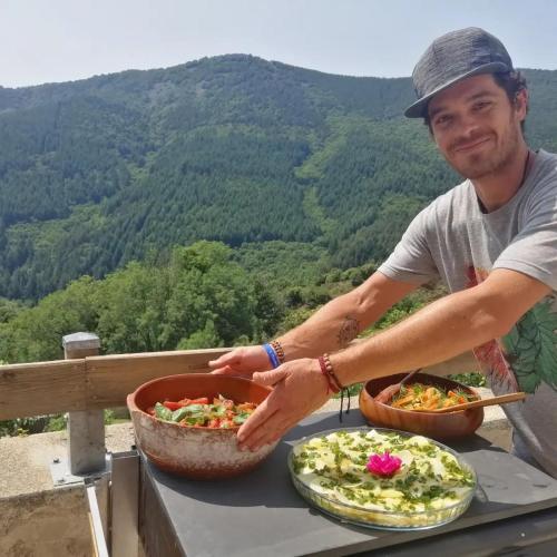a man standing on a table with two plates of food at La Ferme De Chalas in Valgorge