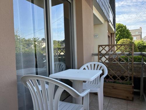 d'une table blanche et de deux chaises sur un balcon. dans l'établissement 541 - Studio en rez-de-jardin à quelques pas de la plage, à Erquy