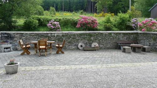 a patio with a table and chairs and a stone wall at Bambi in Eslohe