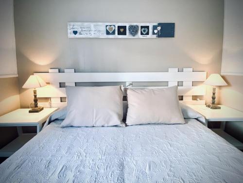 a bedroom with a bed with white pillows and two lamps at Apartments Campanitx - Astbury Formentera in Es Caló