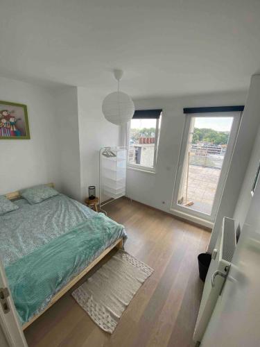 a bedroom with a bed and two large windows at Bel appartement spacieux Verviers in Verviers