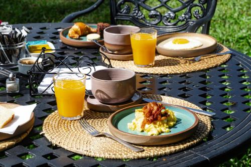 una mesa con platos de comida y vasos de zumo de naranja en El Tránsito Hotel Boutique en Concepción