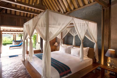 a bedroom with a canopy bed with white curtains at Villa Blue Steps in Yogyakarta