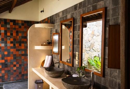 two sinks in a bathroom with two mirrors at Villa Blue Steps in Yogyakarta