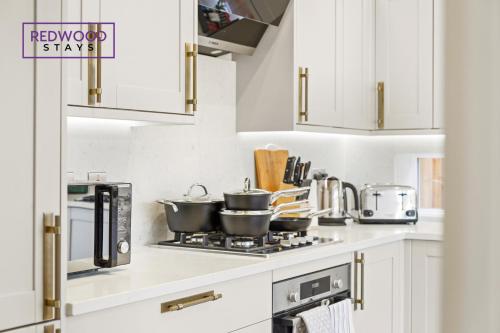 a kitchen with two pots and pans on a stove at Brand New Modern Houses For Contractors & Families with Free Parking, Free WiFi & Netflix By Redwood Stays in Farnborough