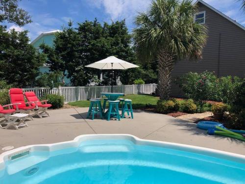 a pool with chairs and a table and an umbrella at Why Knot Getaway. Emerald Isle Oasis in Emerald Isle
