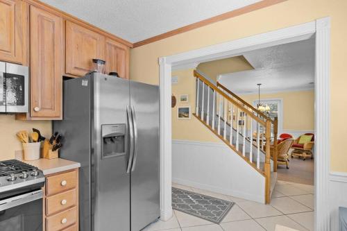 a kitchen with a stainless steel refrigerator and a staircase at Why Knot Getaway. Emerald Isle Oasis in Emerald Isle