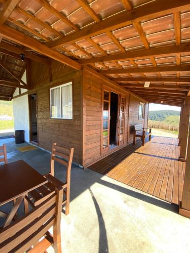eine Veranda einer Holzhütte mit einem Tisch und Bänken in der Unterkunft Aconchego Alto da Serra in Alfredo Wagner