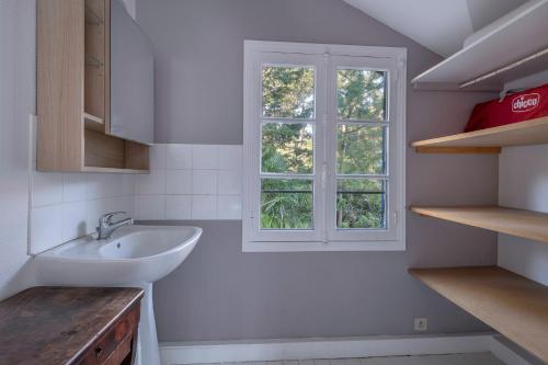 Un baño con lavabo y ventana. en Belle villa bauloise à deux pas de la plage, en La Baule