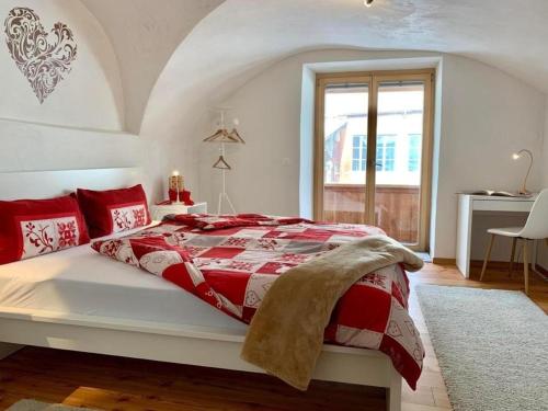 una camera con un letto rosso e bianco e una finestra di Zusammen mit Freiraum - ENGADIN HOLIDAYS a Guarda