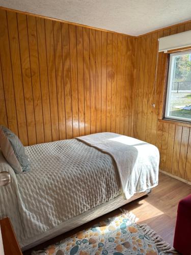 a bedroom with a bed in a wooden wall at Cabañas Kuyén Austral in Hornopiren